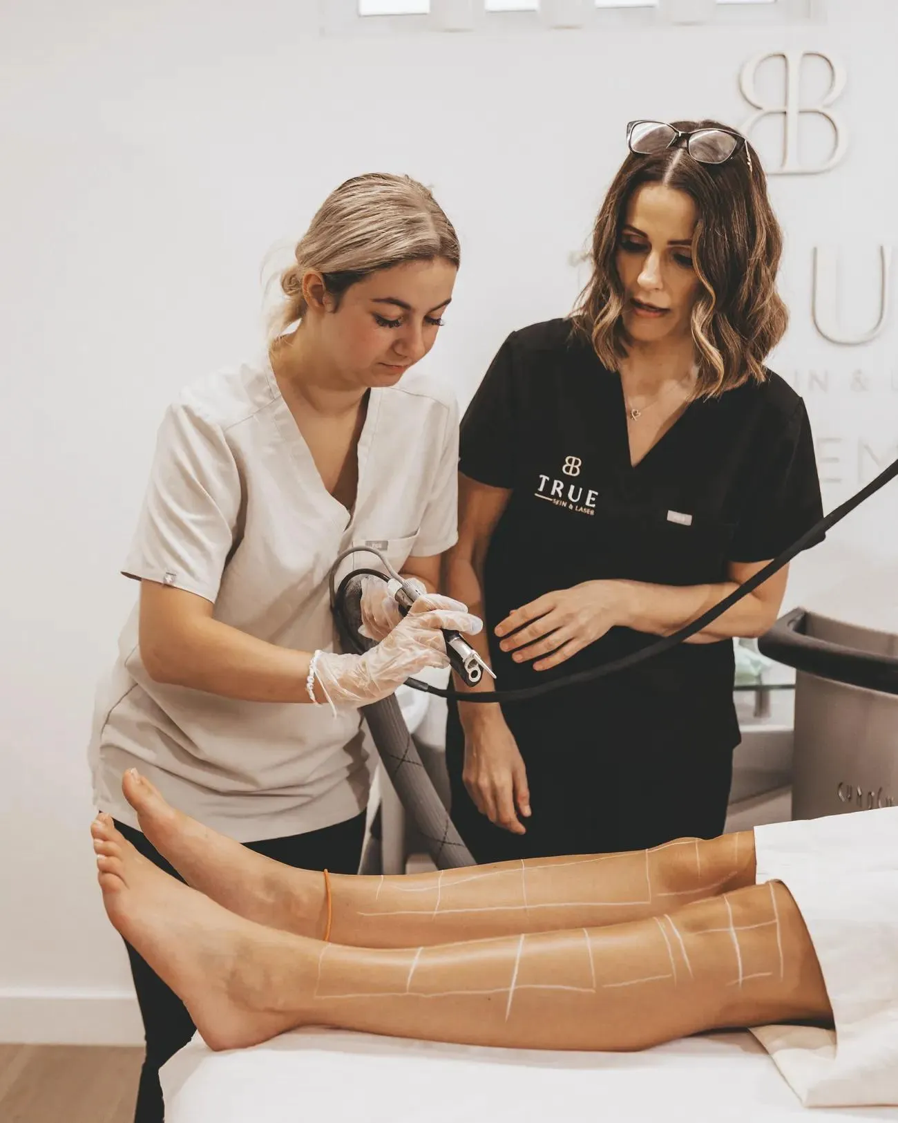 Sarah guiding a student’s hand on the laser handpiece during a practical session