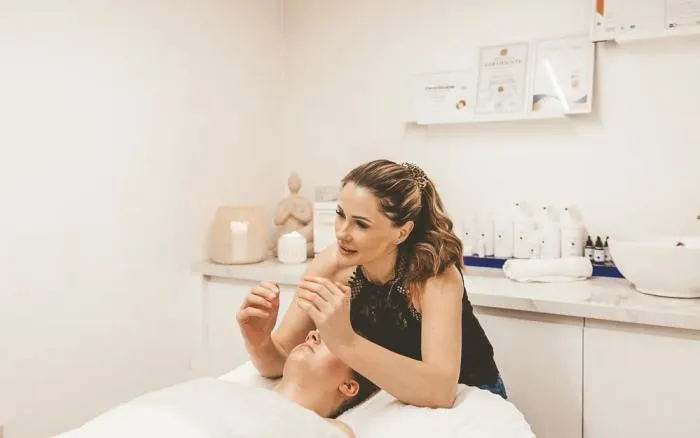Sarah lifting a client's cheek during a TrueLift facial massage in the clinic treatment room