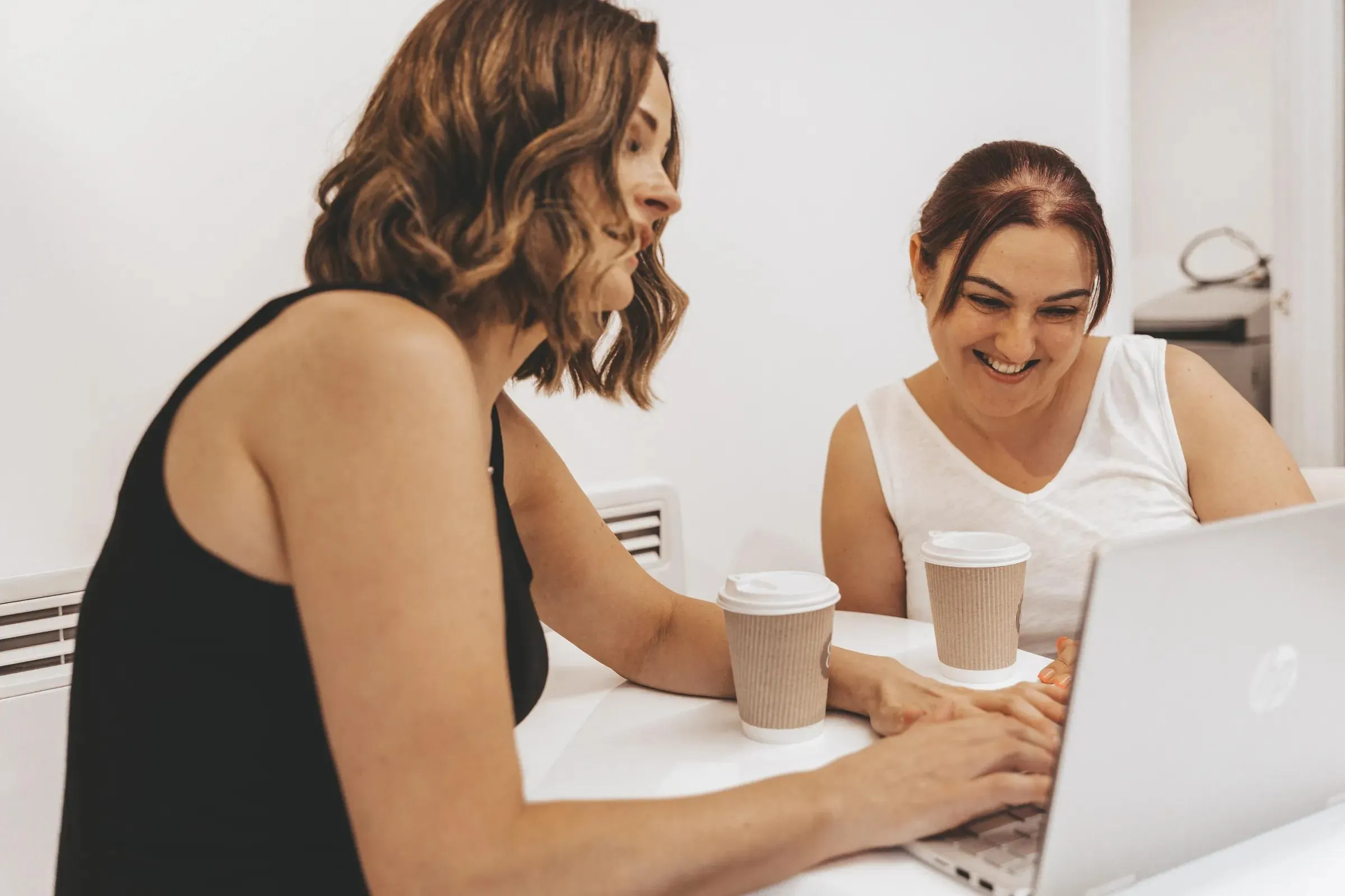 Sarah going through course material on a laptop with a student at the academy