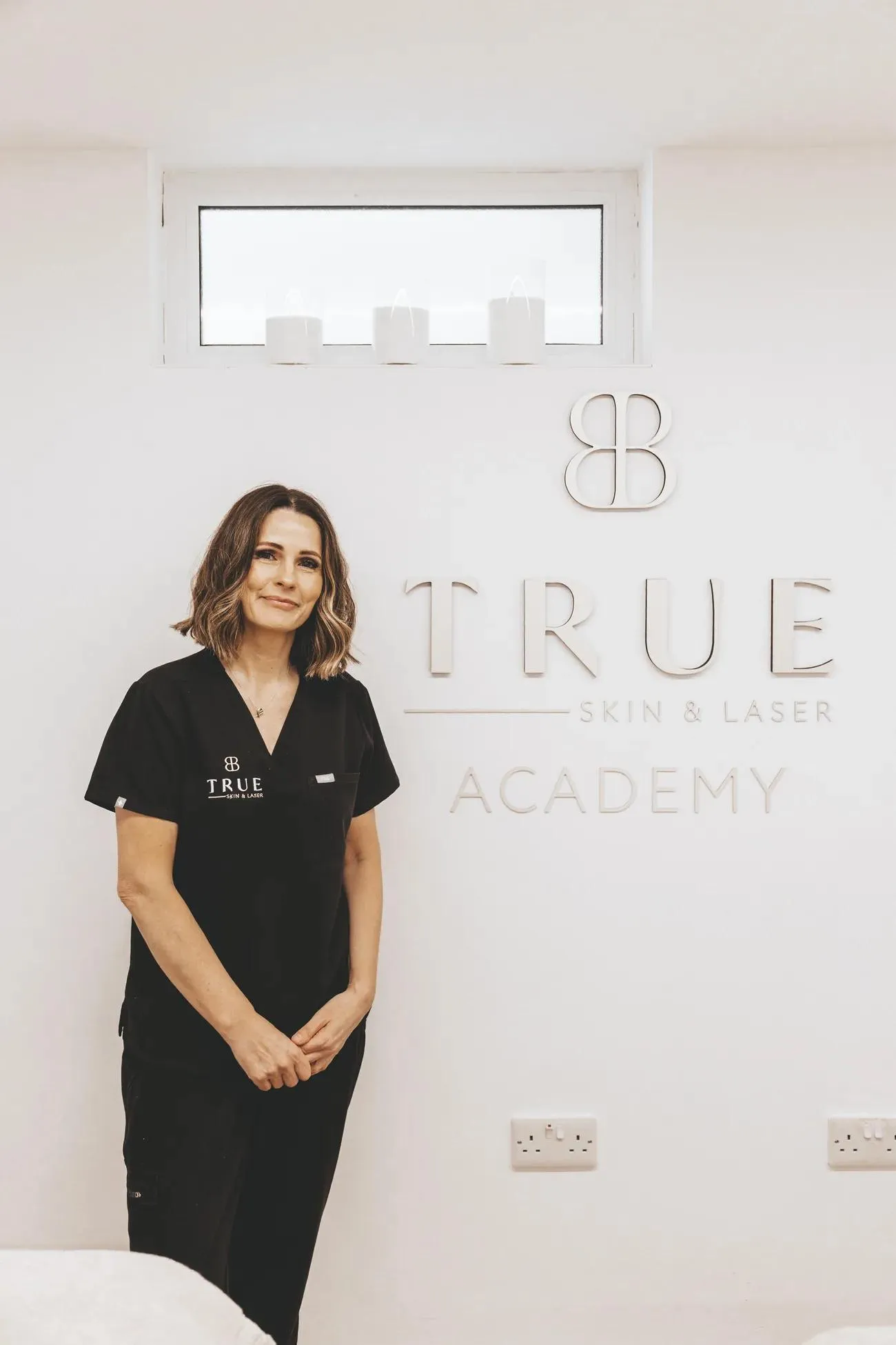Sarah, founder of True Skin and Laser Academy, in front of the academy signage