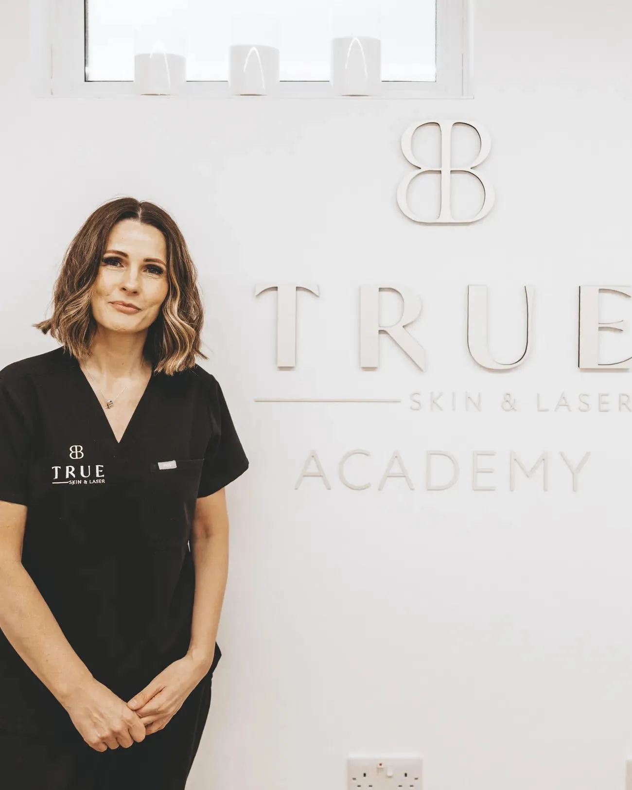 Sarah Bates standing in front of the True Skin & Laser Academy signage at her clinic