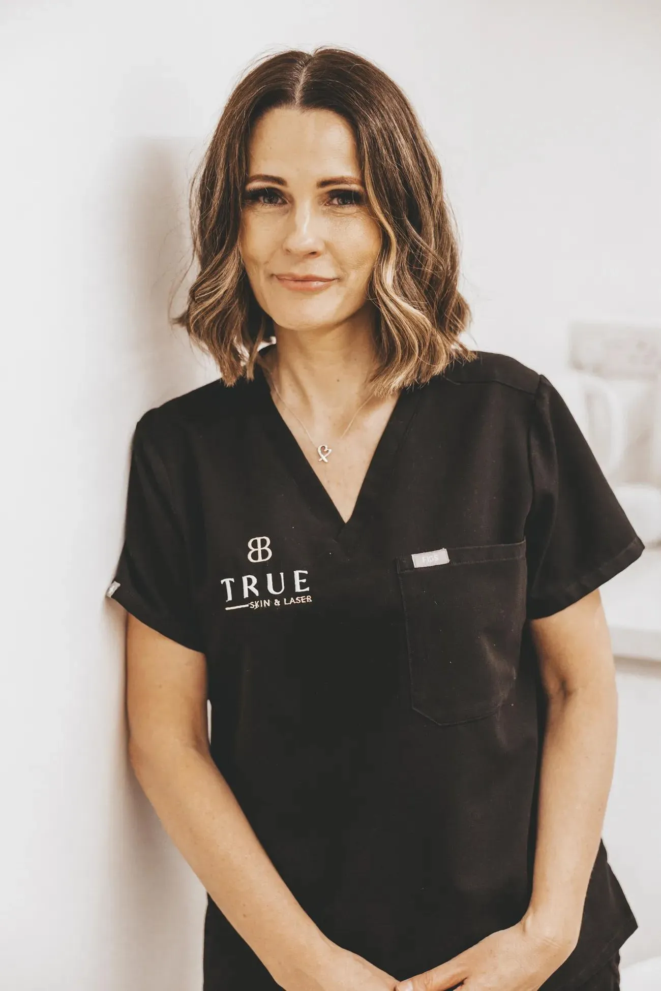 Sarah, founder of True Skin and Laser Academy, in branded black scrubs