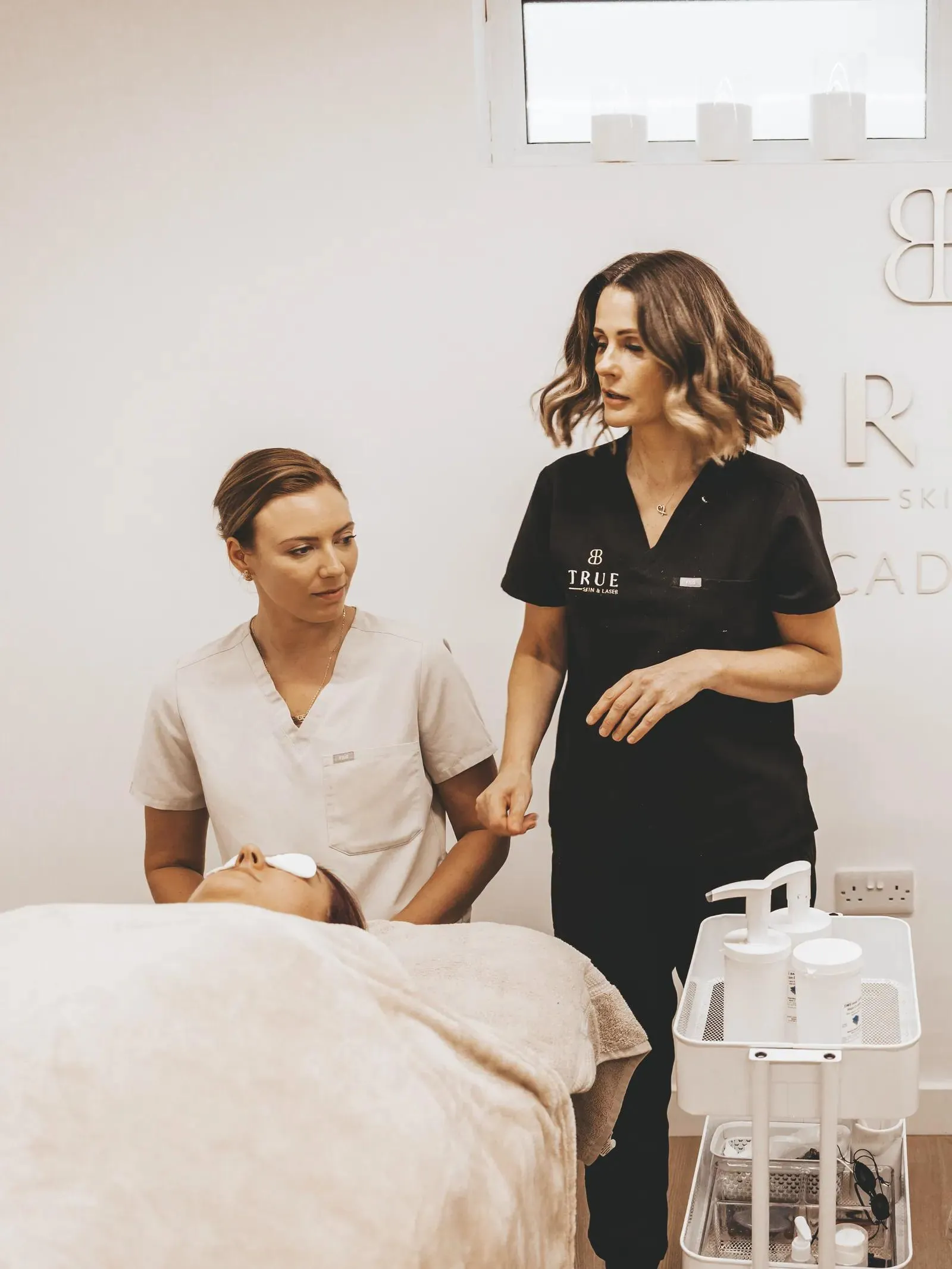 Sarah guiding a student through a facial treatment in the academy training room
