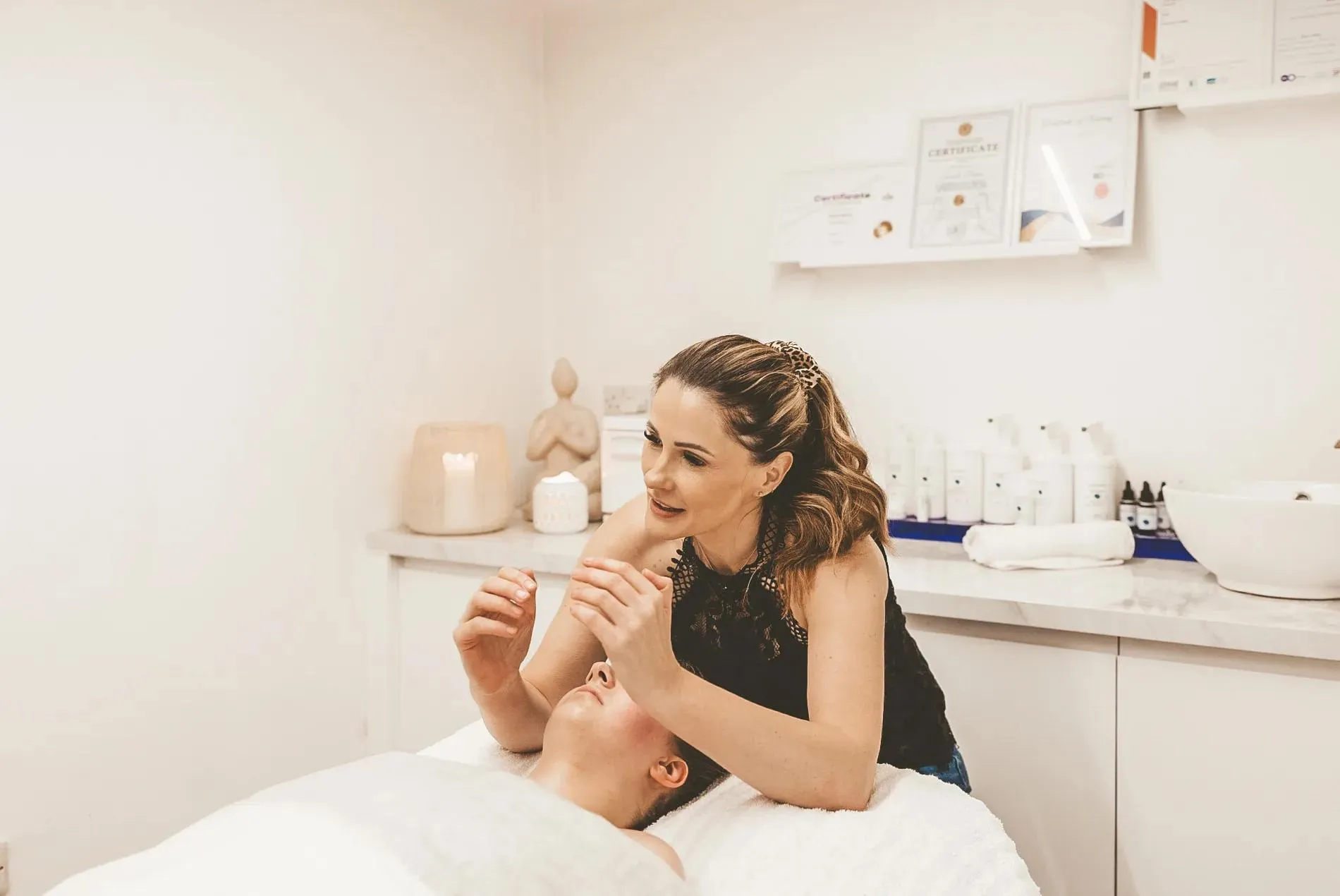 Sarah lifting a client's cheek during a TrueLift facial massage in her treatment room