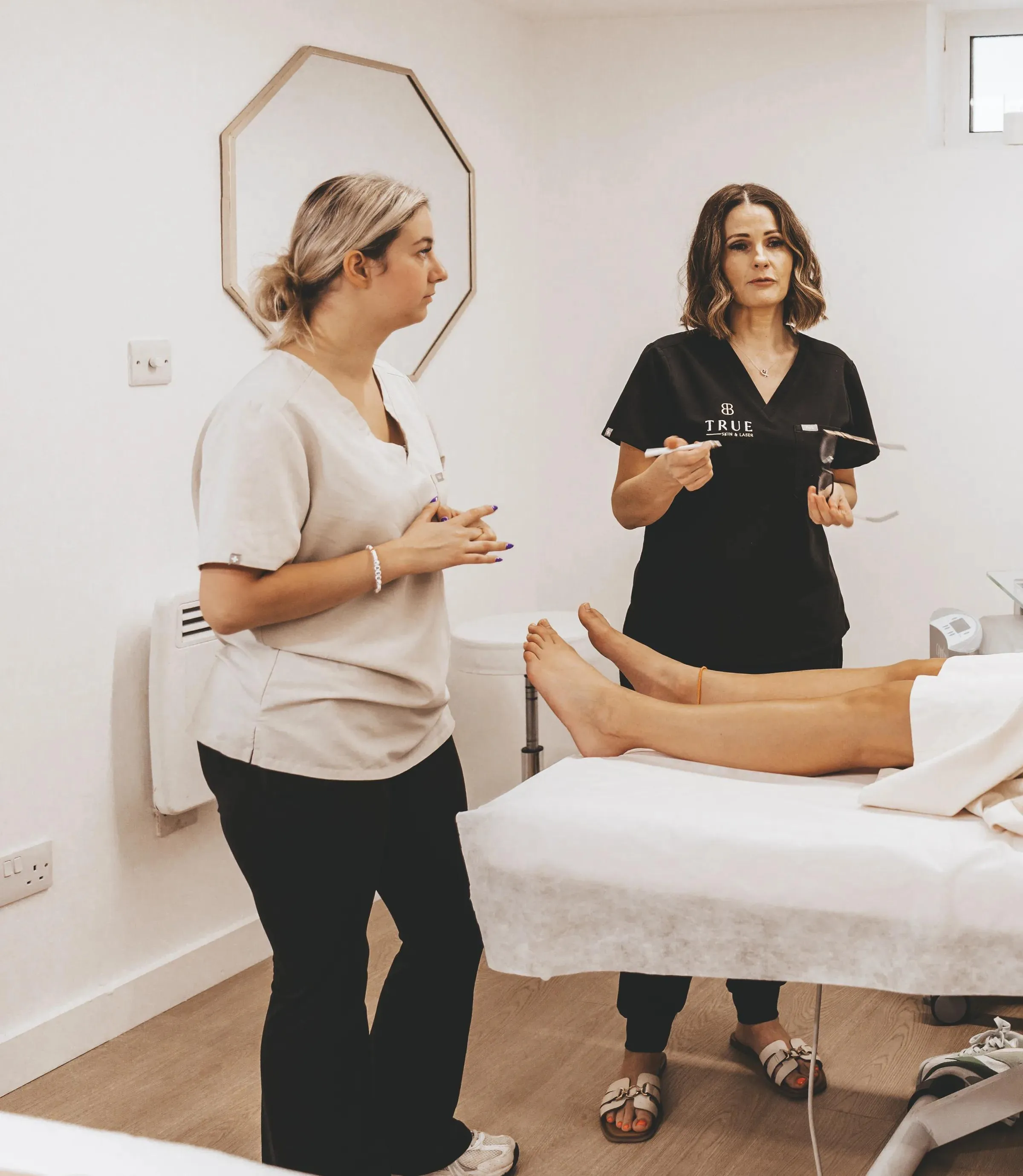 Sarah and a student beside the laser system in the academy treatment room