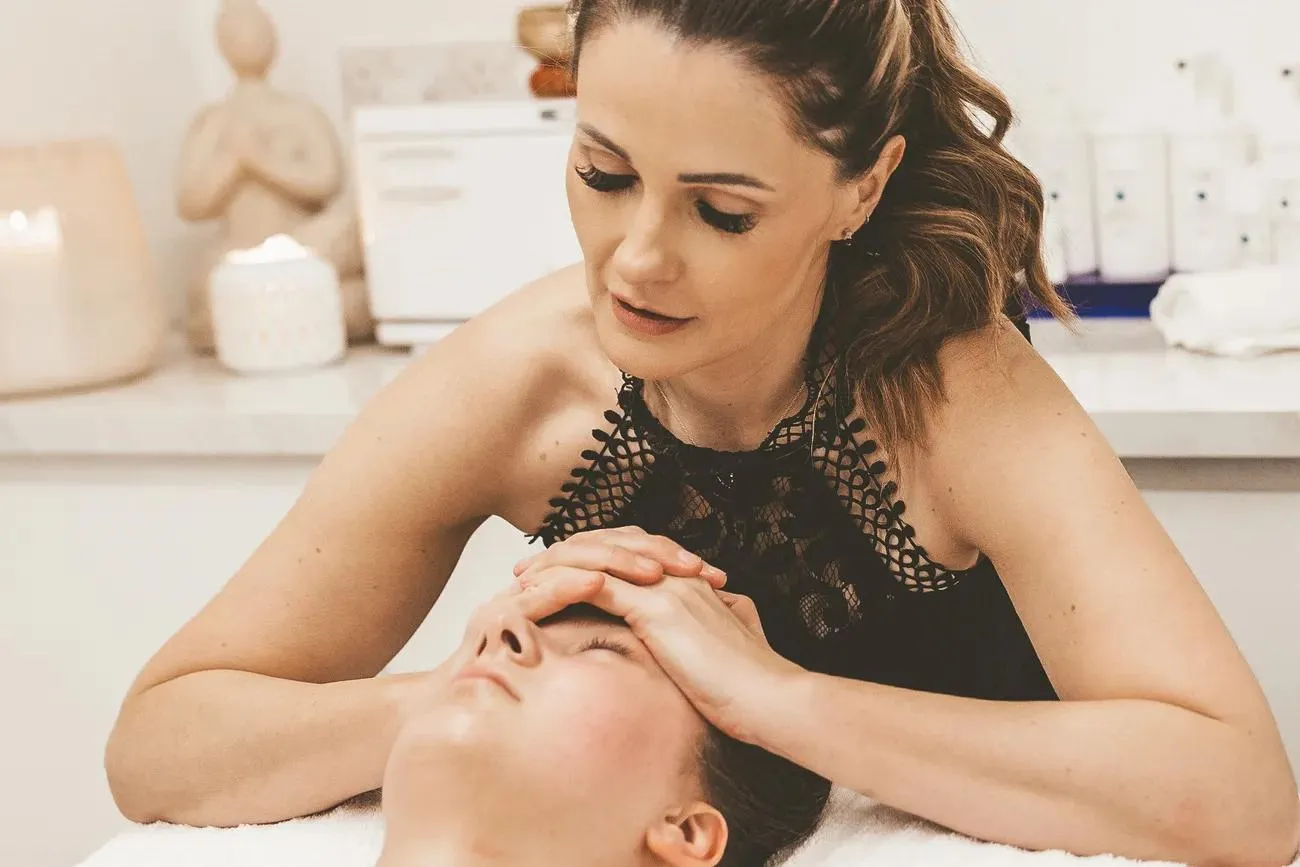 Sarah resting both hands on a client's forehead during a TrueLift treatment