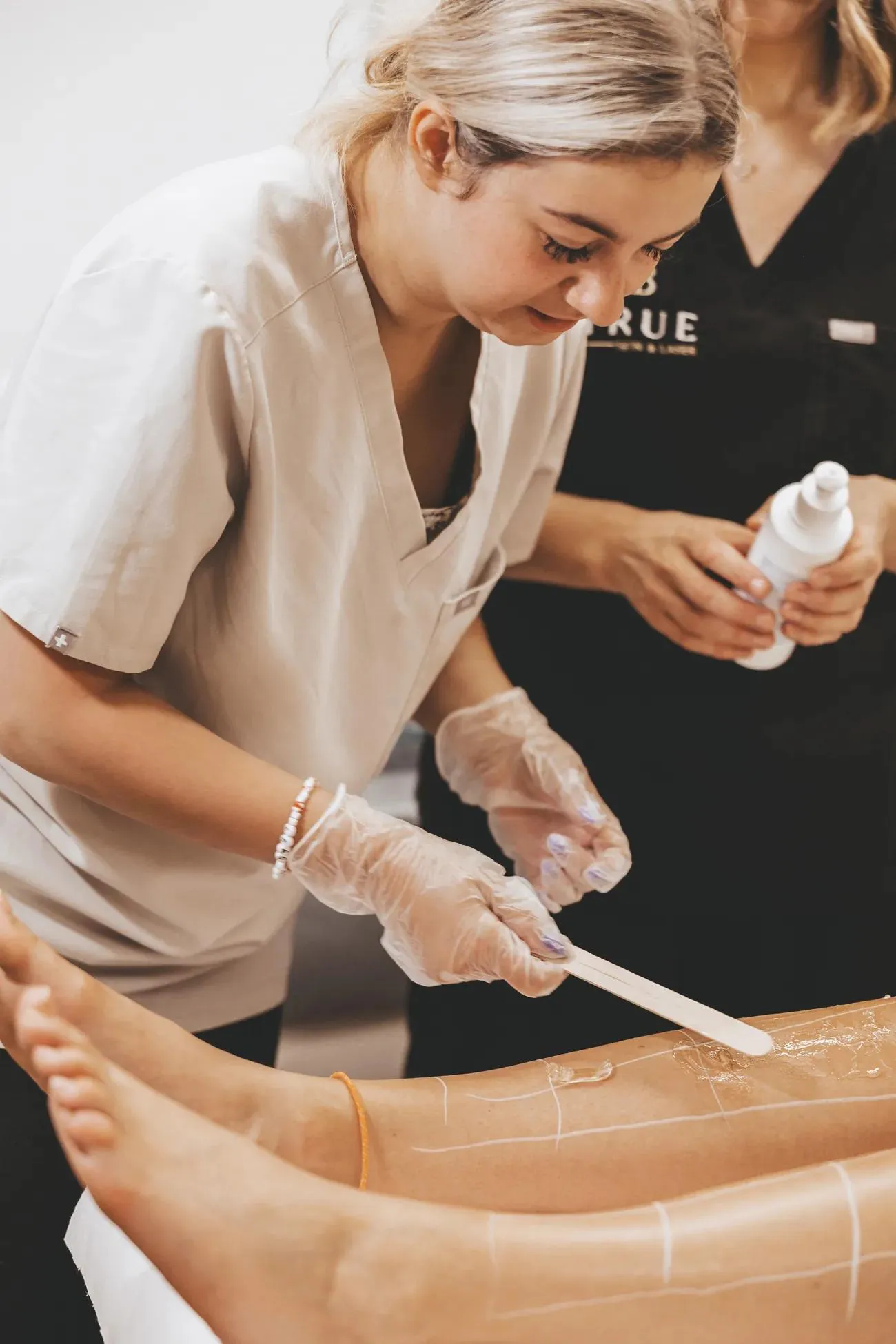 A student marking out the treatment area on a model's leg before a laser session