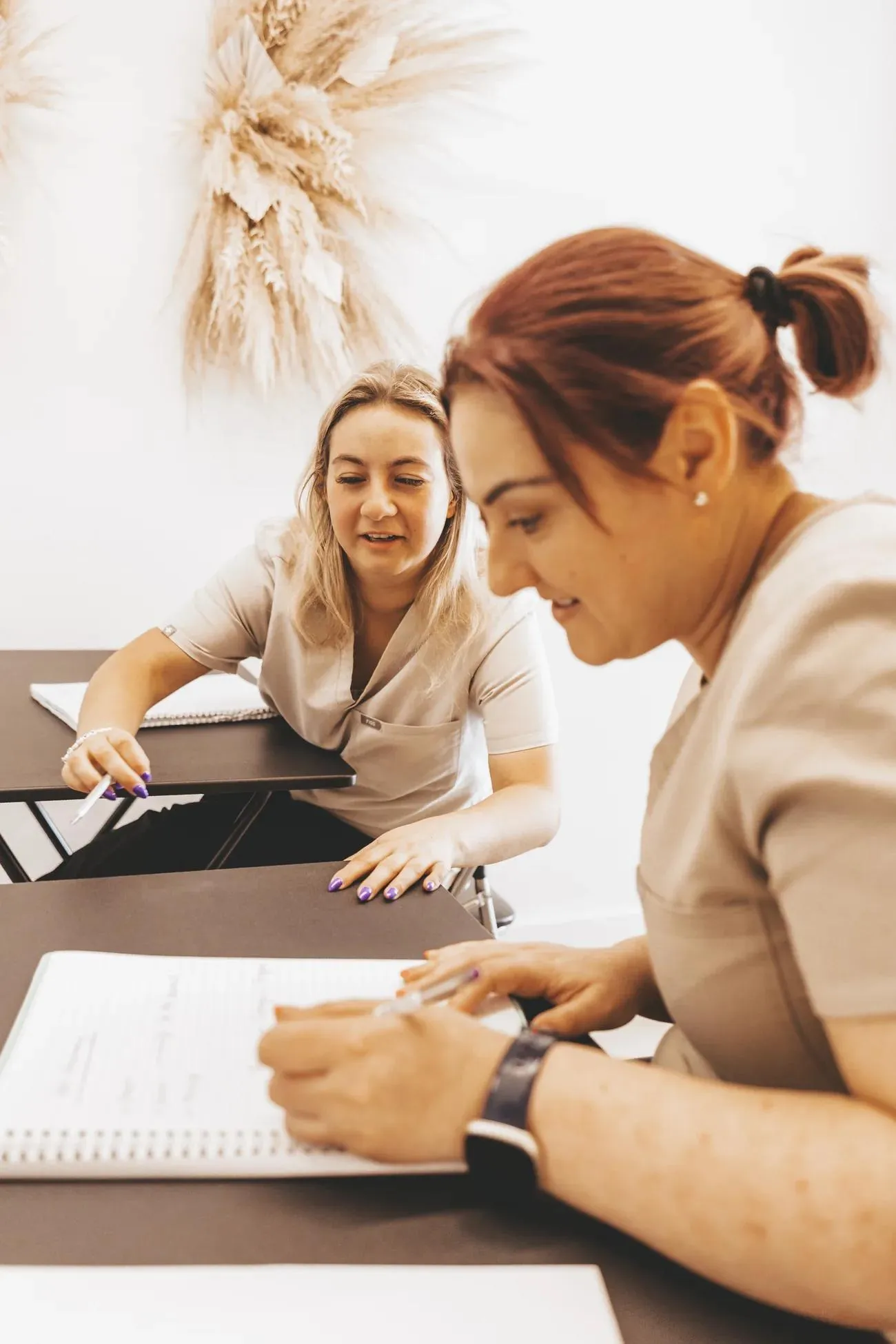 Two students working through the course workbook together at the academy