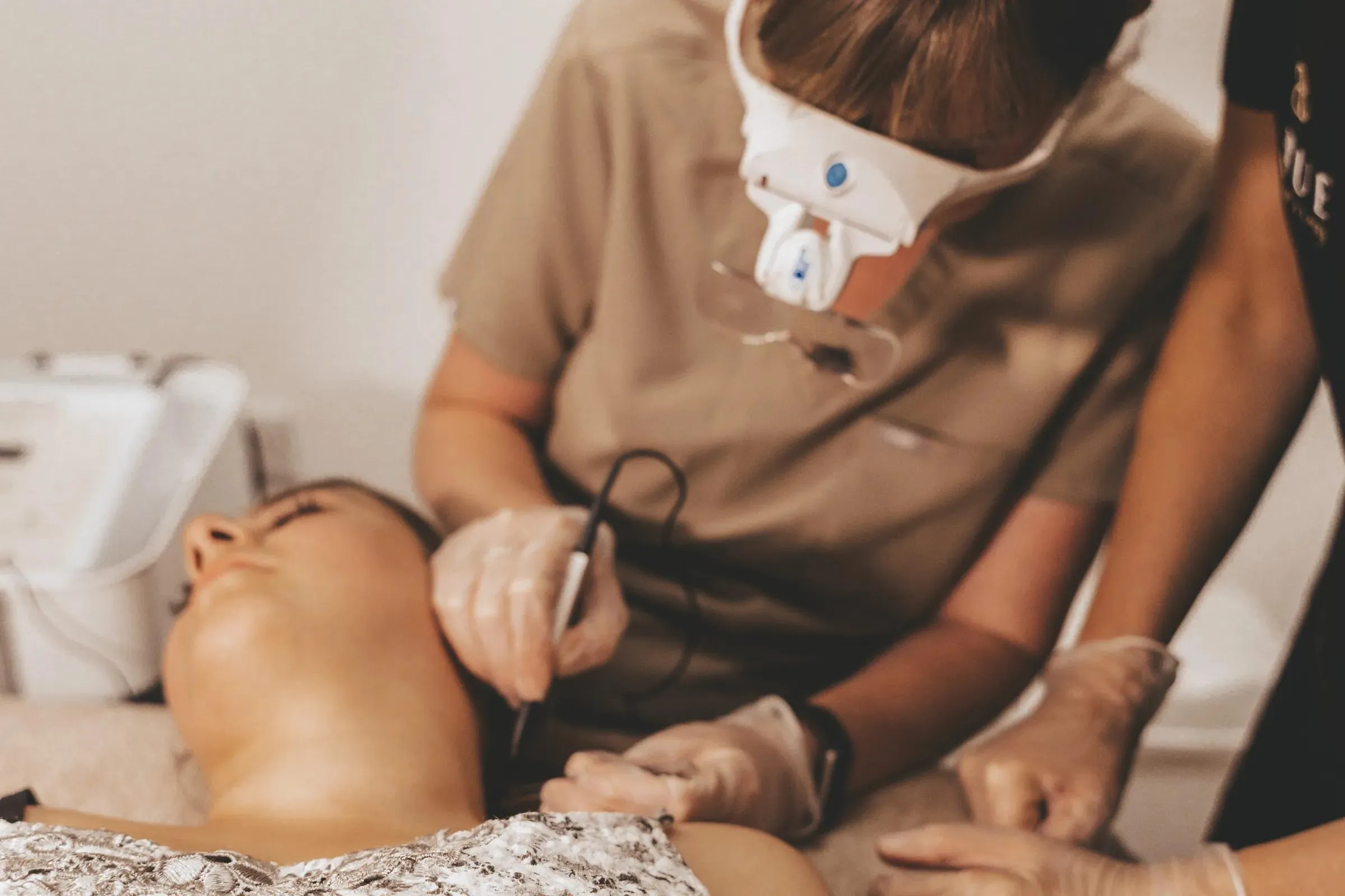 A student treating a client's skin under magnification during advanced electrolysis training